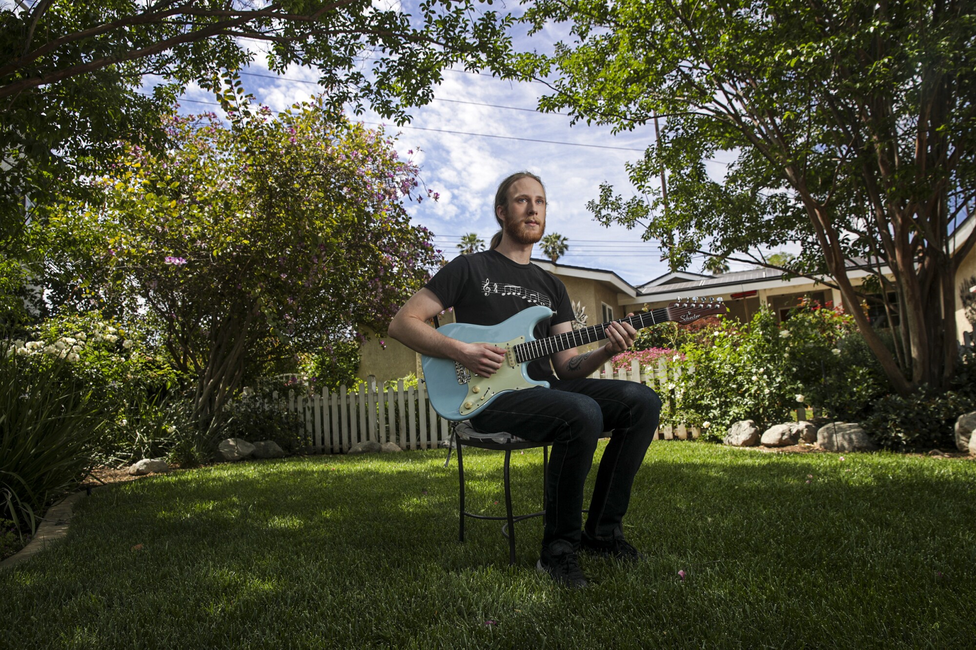 Trevor Jackson sits on a chair holding an electric guitar