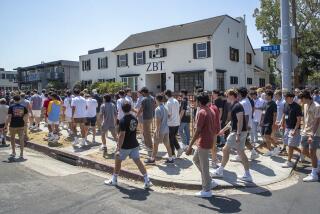 LOS ANGELES, CA -AUGUST 19, 2022:USC students walk by Zeta Beta Tau fraternity house while making their way along USC fraternity row, 28th St. in Los Angeles, during the kick off of rush week. Several fraternities including Zeta Beta TAu formally severed ties with USC earlier this month. Now those frats have come together to form the University Park Interfraternity Council. (Mel Melcon / Los Angeles Times)