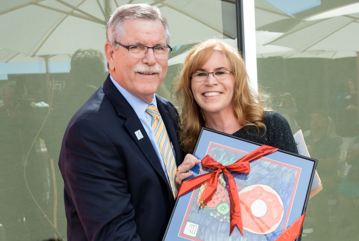 Ronald McDonald House Charities of San Diego president and CEO Chuck Day presents La Jolla resident Trulette Clayes pose with art made by a guest of Ronald McDonald House at the reopening of the Jospeh Clayes III Great Room.