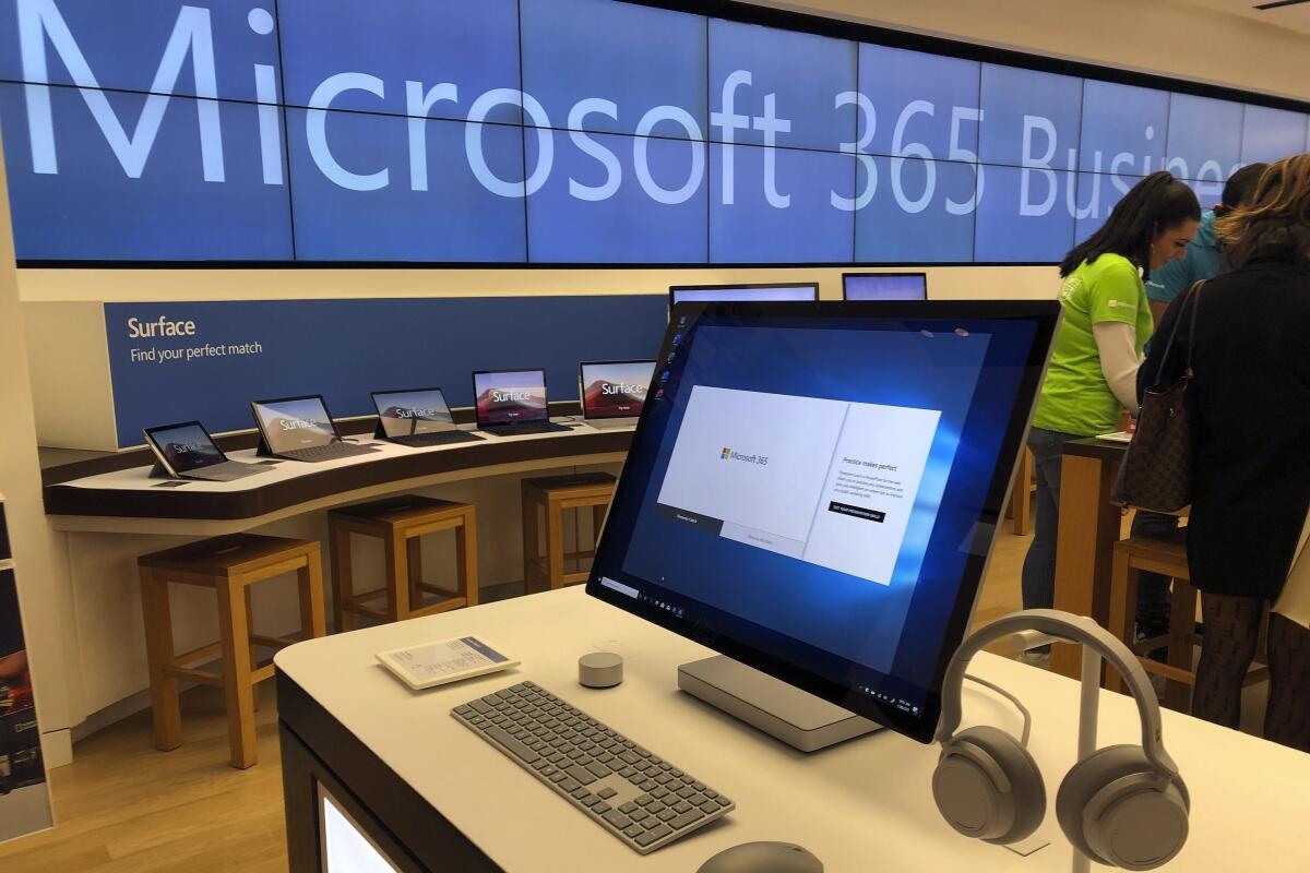 A monitor sits on a desk; laptops line another table.