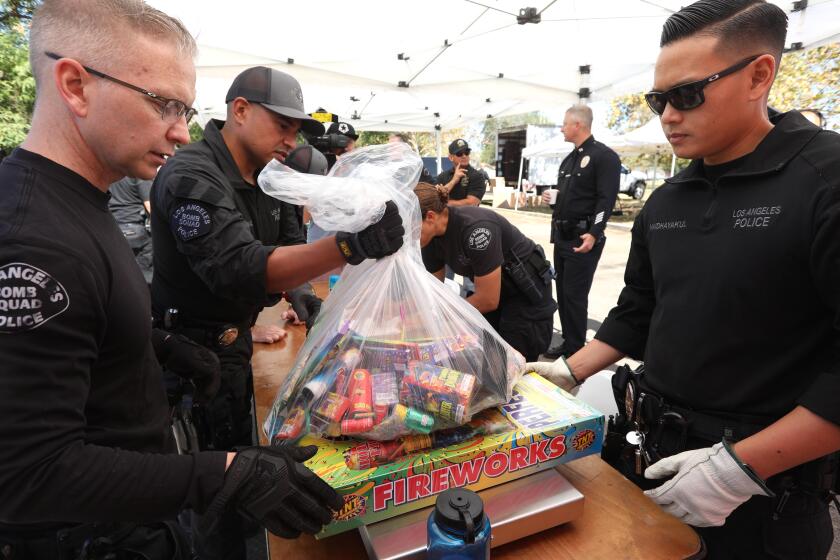 MISSION HILLS, CA - JULY 2, 2022 - - LAPD Bomb Squad officers weigh illegal fireworks that were dropped off during the second annual Anonymous Fireworks Buyback Program in Brand Park in Mission Hills on July 2, 2022. The buyback program was sponsored by the office of city councilwoman Monica Rodriguez. Gift cards for gas, Target stores and Starbucks, along with tickets for a Dodgers game, were given in exchange for fireworks. The gifts were determined by the weight of fireworks that were dropped off. LAPD and LAFD were on hand to accept the fireworks and provide a safe environment to drop off fireworks. According to Laura McKinney, communications director with Councilwoman Monica Rodriguez' office, over 200 pounds of illegal fireworks ranging from aerial mortars, to sky rockets, M-80s and M-1000's were turned in in the first hour of the event. (Genaro Molina / Los Angeles Times)