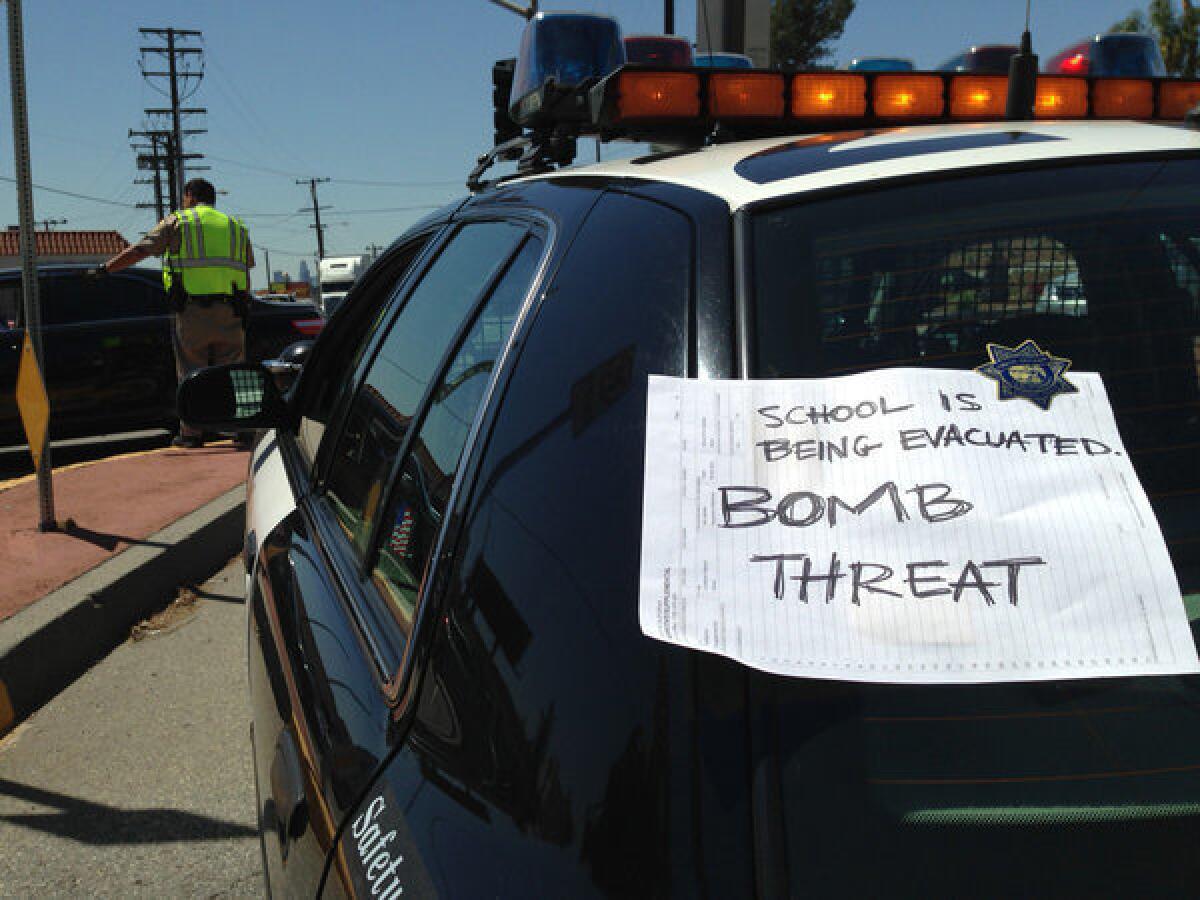 A sign attached to a law enforcement vehicle warns the public of a bomb threat at the Cal State L.A. campus.