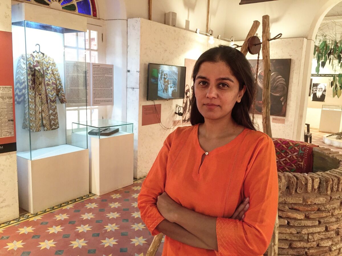 Trustee Mallika Ahluwalia is pictured in one room of the Partition Museum. Displayed at left are a coat and briefcase donated by survivors.