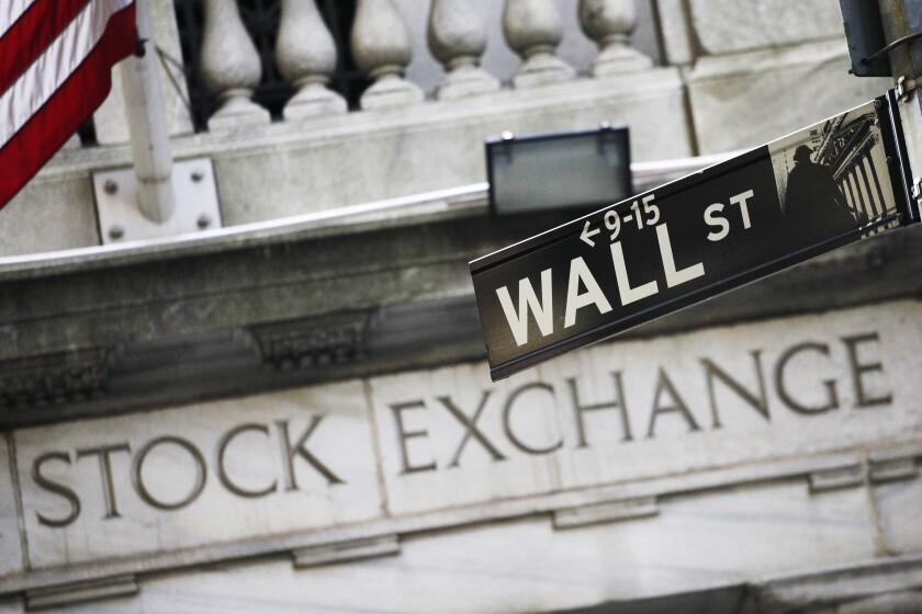A Wall St. street sign in front of a building with the words "Stock Exchange" on it.