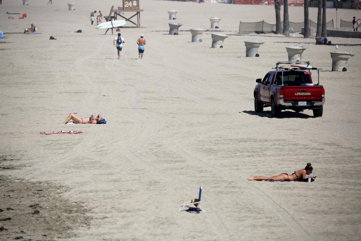 A day after Newport Beach reopened its beaches to recreational activities, lifeguards patrol the sand at the Newport Pier on May 7.