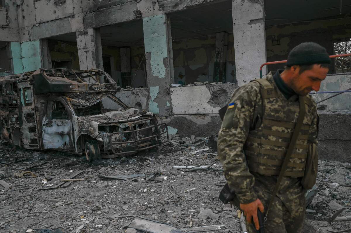 A Ukrainian soldier stands outside a school hit by Russian rockets in southern Ukraine in April.