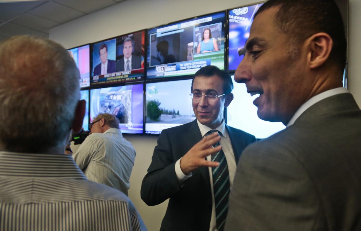 Ehab Shihabi, second from right, interim CEO for Al Jazeera America, gestures as he chats with newsroom staff after the network's first broadcast.