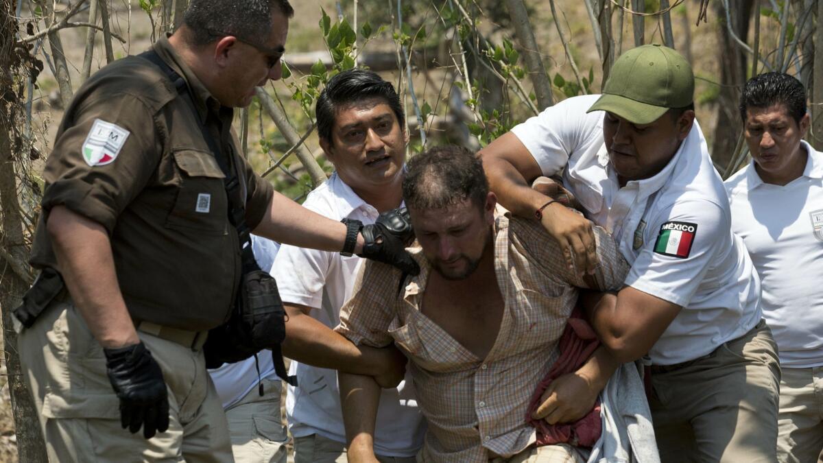 A Central American migrant is detained April 22 by Mexican immigration agents on the highway to Pijijiapan, Mexico.
