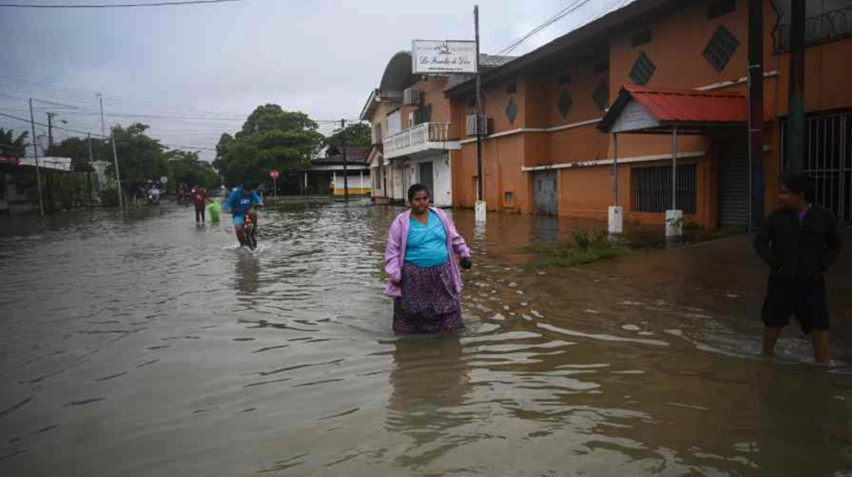 La gente camina en una calle inundada debido a las fuertes lluvias 