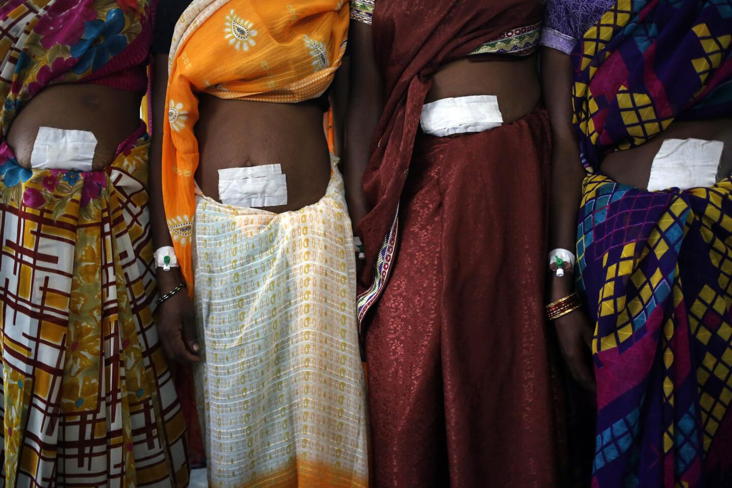 Women, who underwent sterilization surgery at a government mass sterilization camp, pose for pictures inside a hospital in the eastern India.