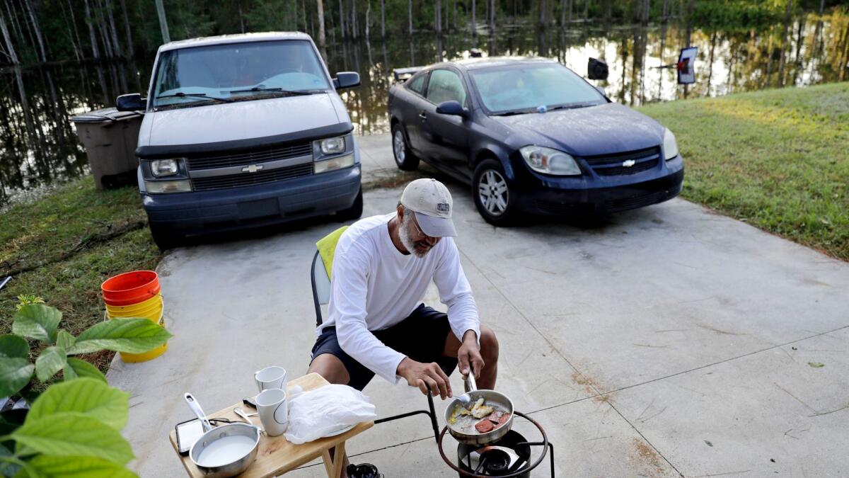 With his Fort Myers, Fla., neighborhood flooded, Cesar De La Cruz makes breakfast Sept. 12 on a propane stove in his driveway. (David Goldman / Associated Press)