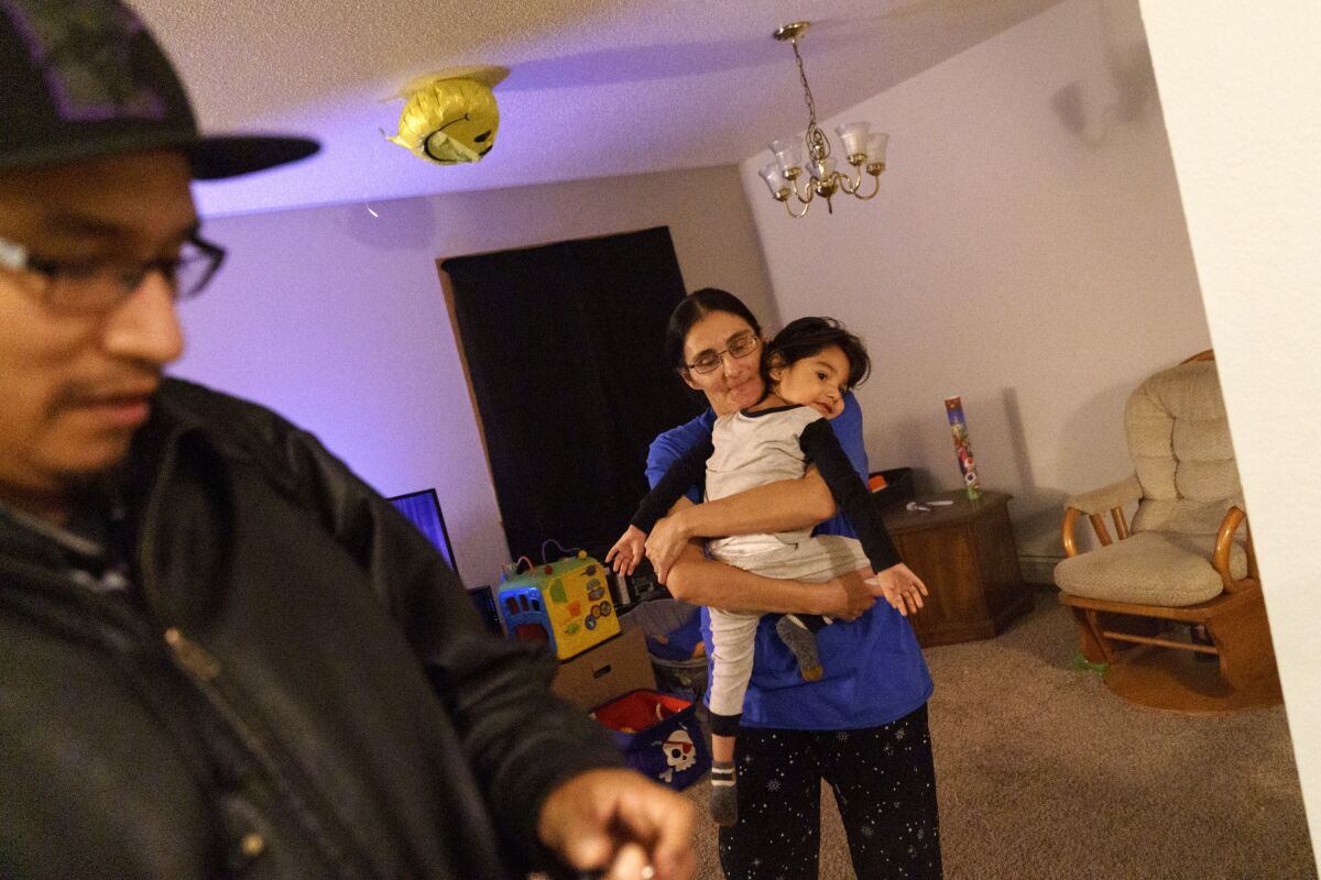 Georgianna Garbow-Warren holds her son as her husband leaves to work an overnight shift.