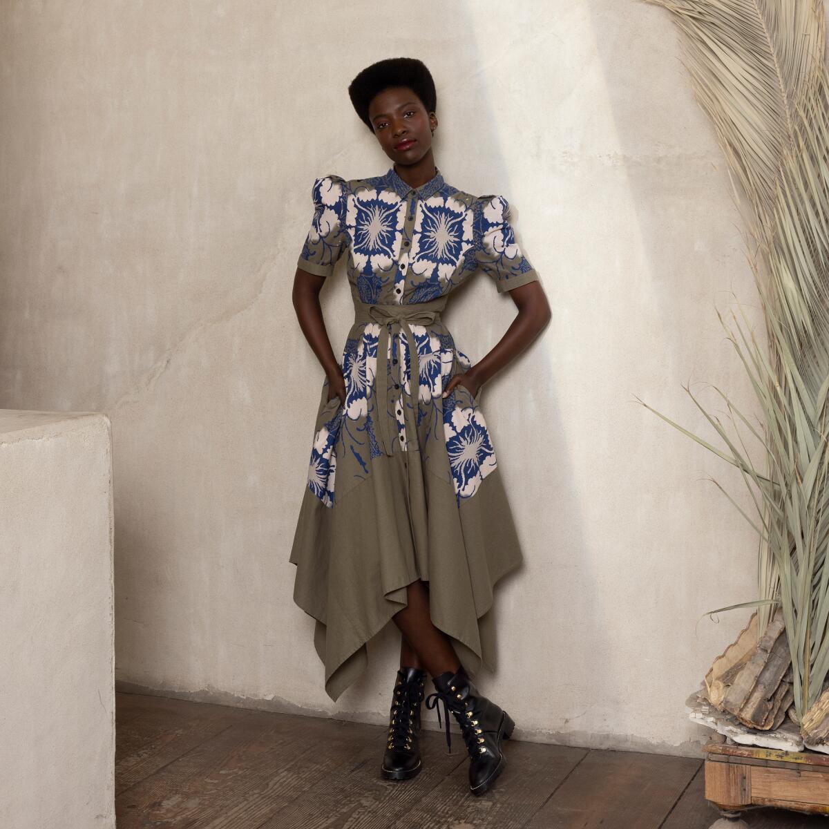 A woman modeling an olive drab dress with blue-and-white patterned panels