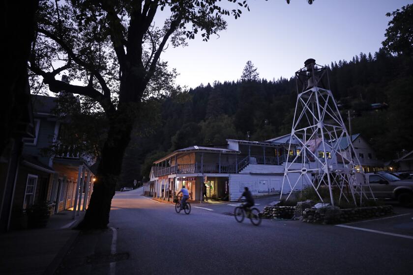 DOWNIEVILLE, CA -- SEPTEMBER 20, 2019: Bicyclists ride through town at dusk in Downieville. In 1851, a woman named Juanita, also known as Josefa, was lynched in this small town north of Sacramento. A miner allegedly attempted to assault her and she later stabbed him in the heart. (Myung J. Chun / Los Angeles Times)