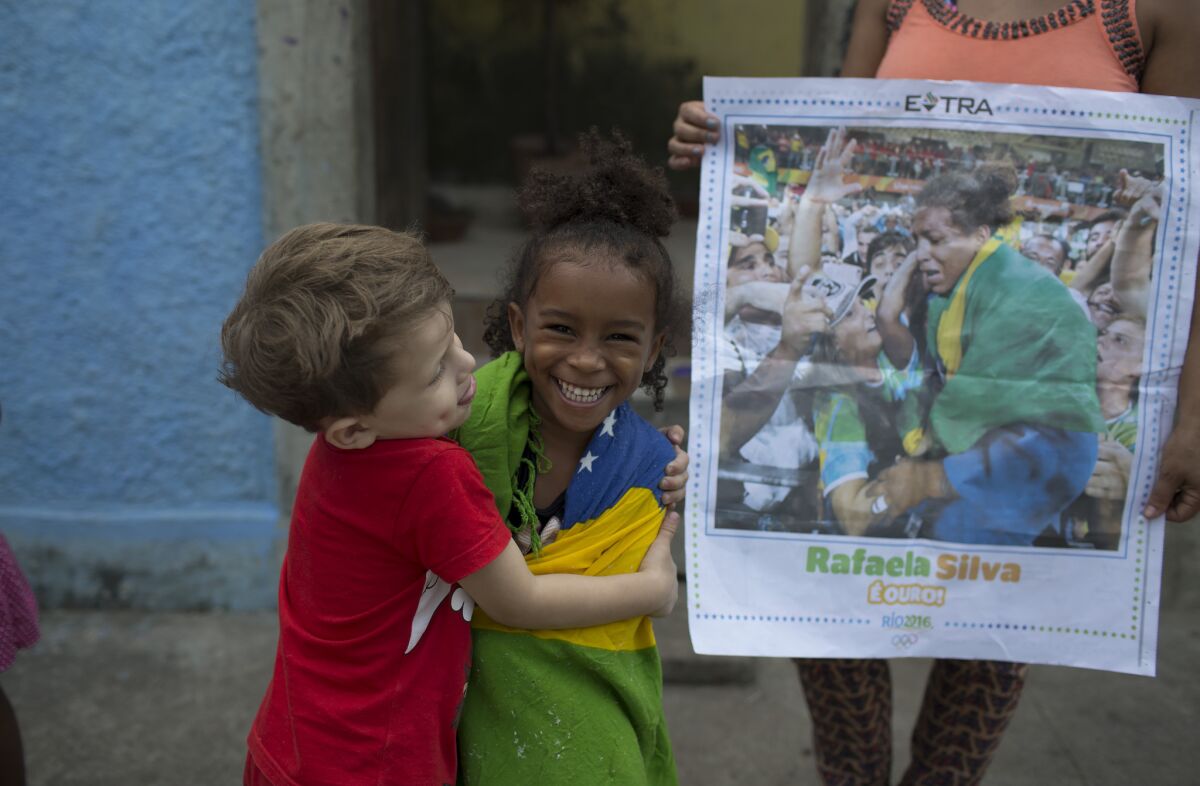 Wrapped in the Brazilian flag, 4-year-old Giovana Silva celebrates the gold medal of her cousin, Rafaela Silva.