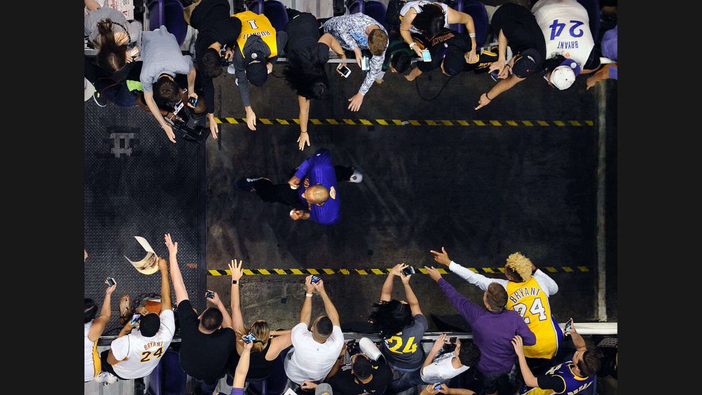 Lakers Kobe Bryant runs on to the court as fans try to reach out before a game with the Suns.