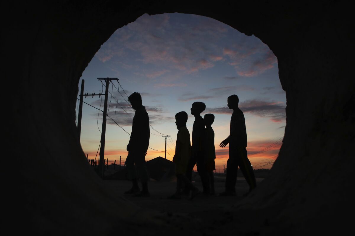 Seen through a large pipe, a group of boys walk together after they offered food at a Buddhist pagoda during the Pchum Ben festival (Ancestors' Day) in the village of Kob Srov, on the outskirts of Phnom Penh, Cambodia, early Sunday morning, Sept. 6, 2020. The traditional 15-day holiday pays respects to deceased relatives. (AP Photo/Heng Sinith)
