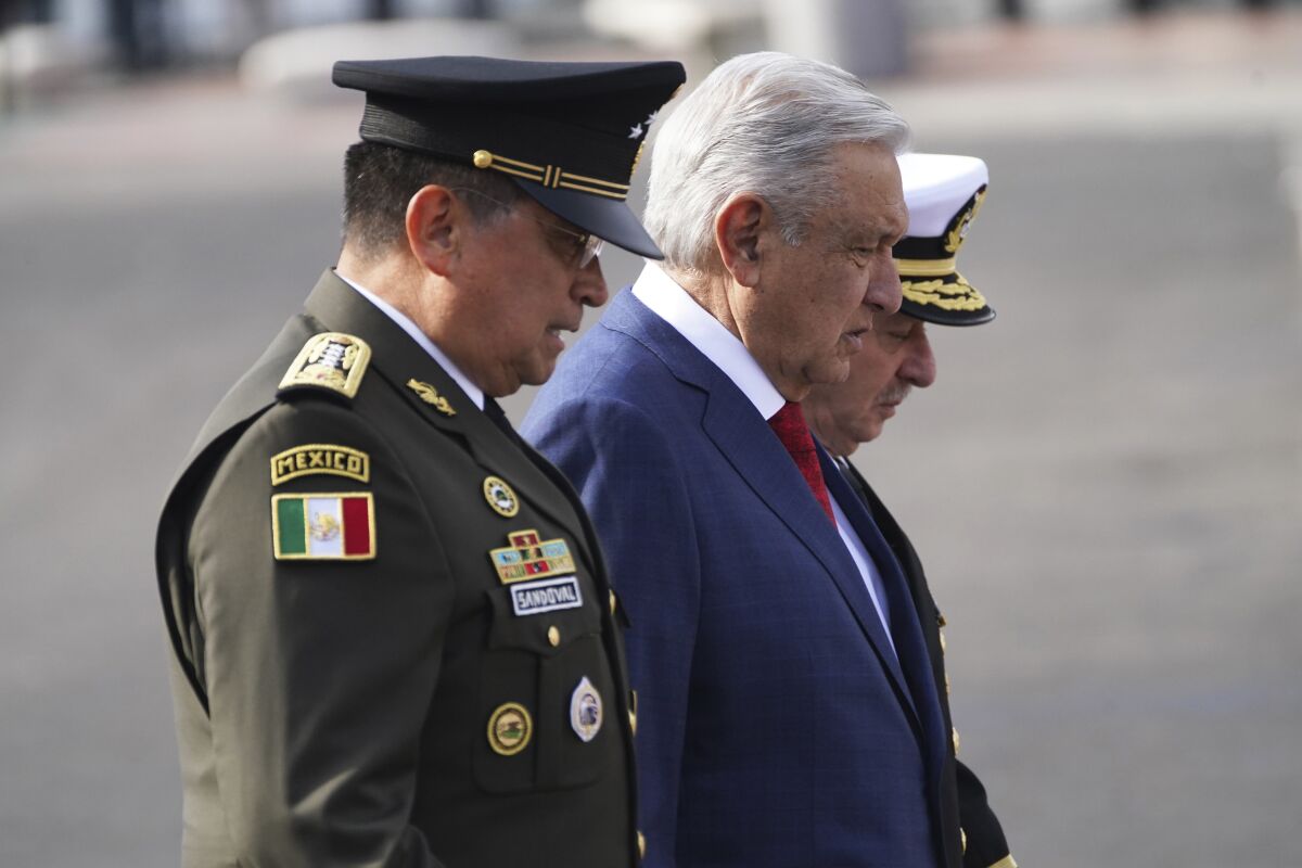 FILE - Mexican President Andres Manuel Lopez Obrador, center, Defense Secretary Luis Crescencio Sandoval, left, and Navy Secretary Vidal Francisco Soberon walk through the Zocalo during the Independence Day military parade in Mexico City, Sept. 16, 2022. A massive trove of emails from Mexico’s Defense Department is among electronic communications taken by a group of hackers from military and police agencies across several Latin American countries, Obrador confirmed Friday, Sept. 30. (AP Photo/Marco Ugarte, File)
