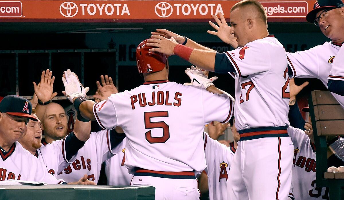 Center fielder Mike Trout (27) and other Angels congratulate first baseman Albert Pujols after he hit a solo home run against the A's in the seventh inning Friday night.