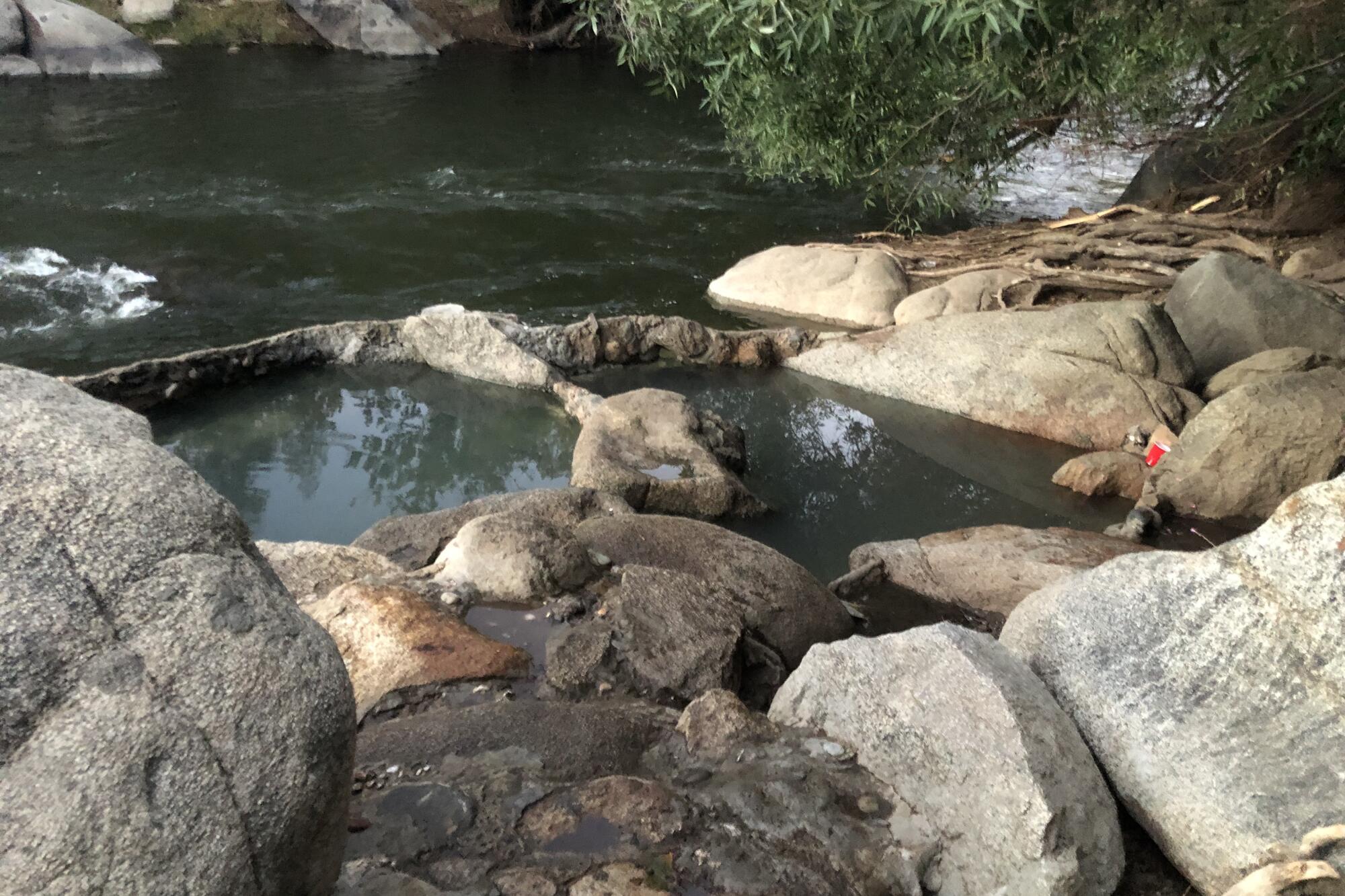 Rock and mortar soaking tubs located on the bank of a river.