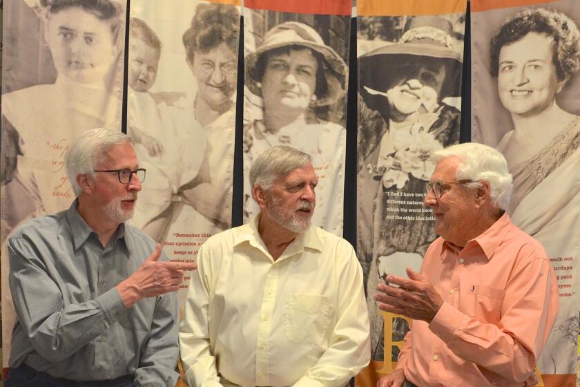 Kent, Craig and John Scudder compare memories with a vintage photo collection at Balboa Island Museum.