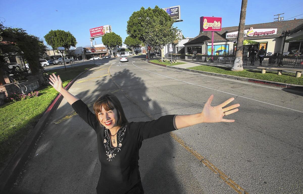 Community activist Linda Williamson stands on a right-turn lane in Granada Hills where she envisions a new pedestrian plaza. She has her backers -- and firece opposition from the one person who could block her: the owner of the yogurt shop in the background.