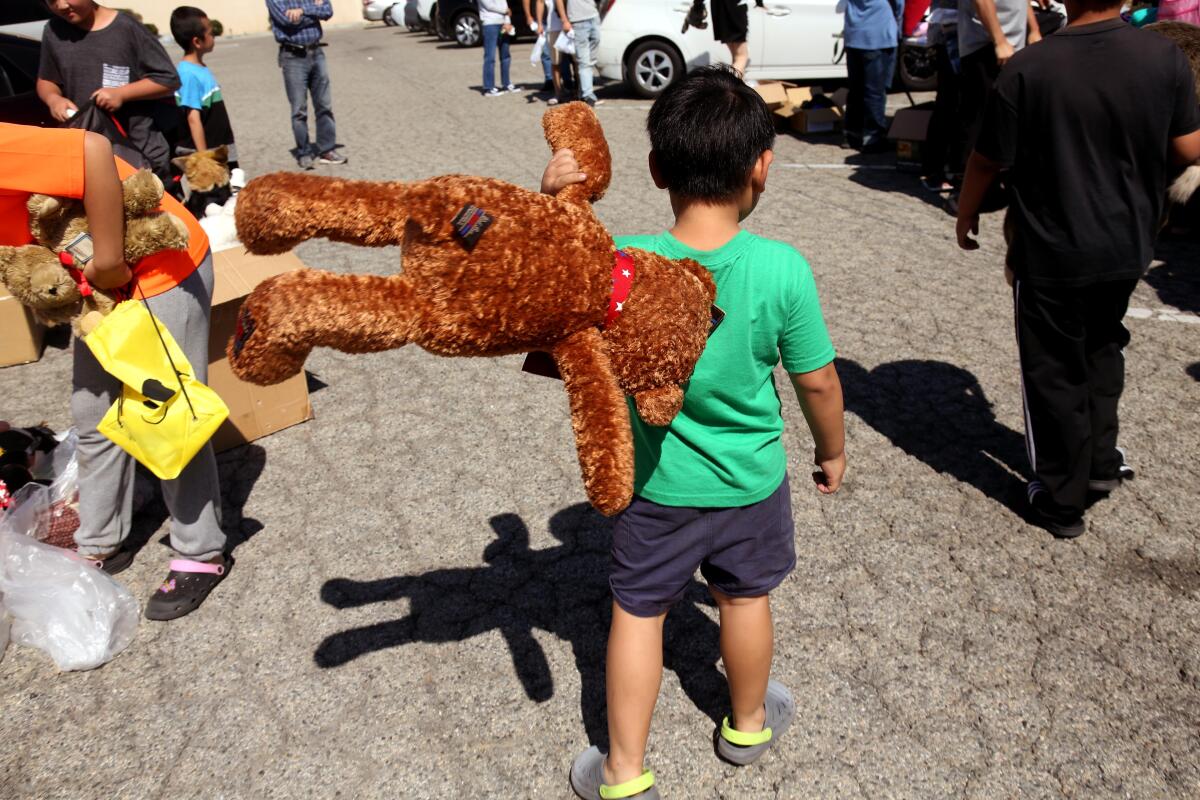 A migrant child walks away with a new stuffed animal over his shoulder.