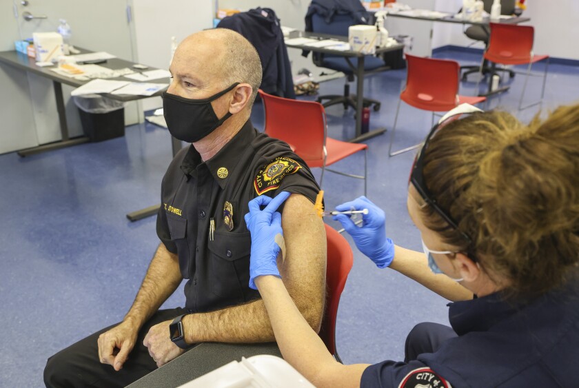 Engineer/paramedic Bonnie Breckenridge gives a COVID-19 vaccine to Fire Chief Colin Stowell.