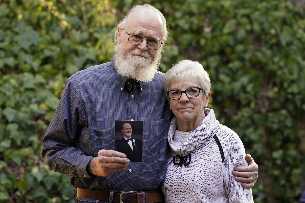 Clark McIlvain and Kathleen McIlvain hold a photo of their son, Charles McIlvain, at their home on Thursday, Dec. 3, 2020, in Woodland Hills, Calif. Charles McIlvain was one of 34 people killed when dive boat Conception caught fire and sank off the coast of California on Sept. 2, 2019. (AP Photo/Ashley Landis)