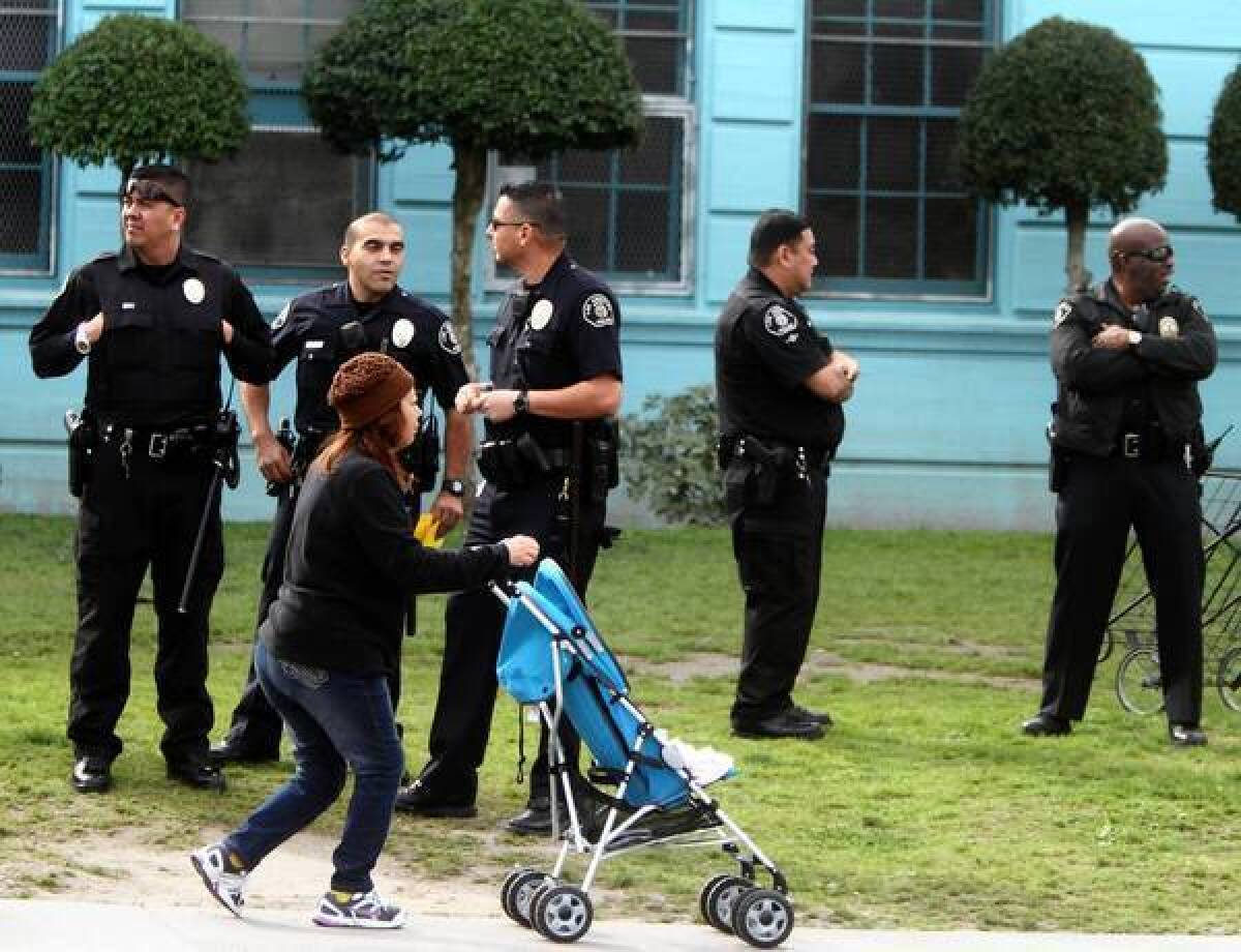 A mother walks past Los Angeles police officers in front of Miramonte Elementary School, where teachers and parents conducted a protest demonstration last year. Former teacher Mark Berndt allegedly abused 58 students at the school.