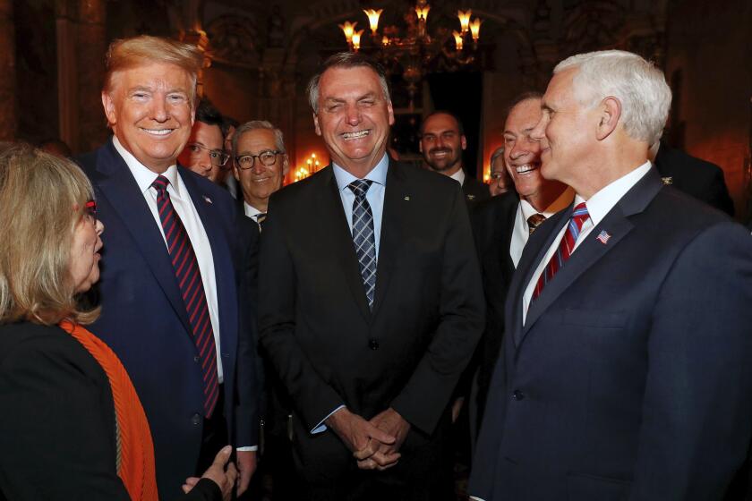 In this March 7, 2020 photo provided by Brazil's presidential press office, Brazil's President Jair Bolsonaro, center, stands with President Donald Trump, second from left, Vice President Mike Pence, right, and Brazil's Communications Director Fabio Wajngarten, behind Trump partially covered, during a dinner in Florida. Wajngarten tested positive for the new coronavirus, just days after the trip, according to Bolsonaro's communications office on Thursday, March 12, 2020. (Alan Santos/Brazil's Presidential Press Office via AP)