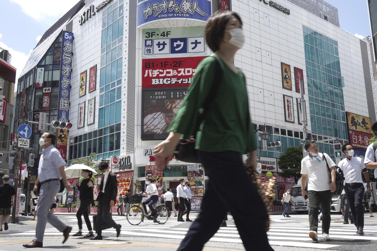 Masked pedestrians walk around a Tokyo intersection.