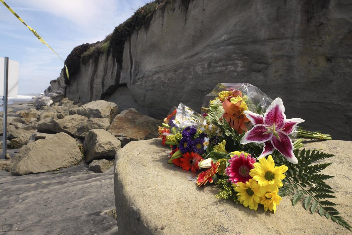 Hayne Palmour IV  U-T A bouquet of flowers lies on some of the sand rock debris from Friday’s bluff collapse, which killed three women, near the Grandview Beach access in Encinitas. Encinitas Lifeguard Capt. Larry Giles said Saturday that a lifeguard will be posted near the collapse zone.