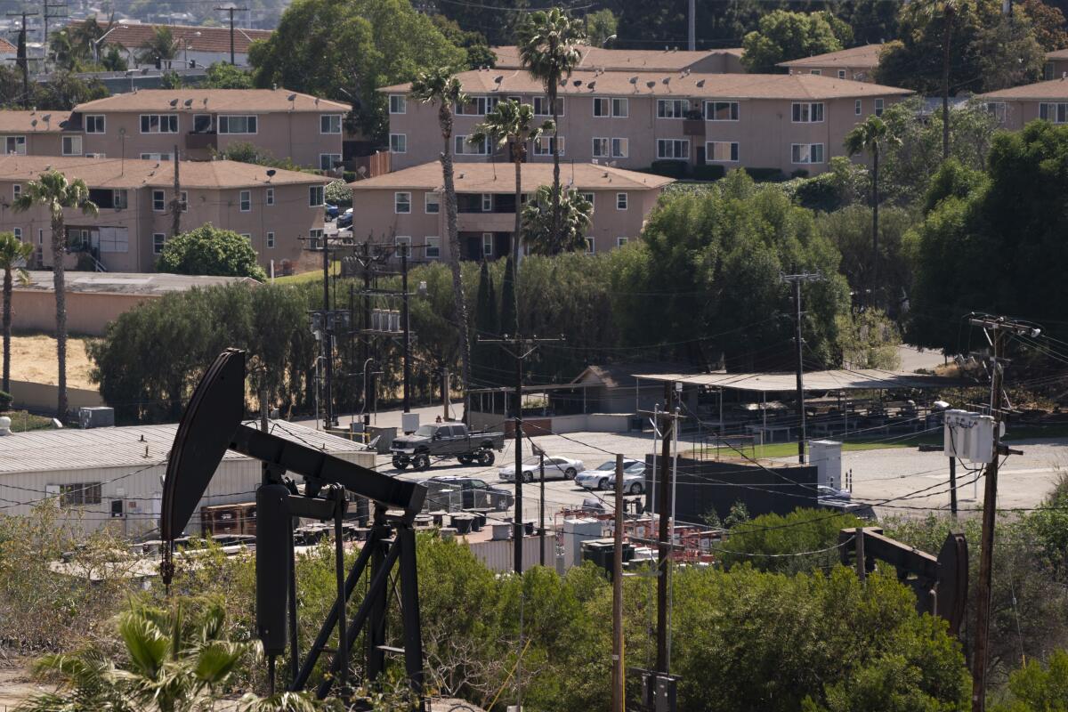 Pump jacks operate in a field near apartment buildings.