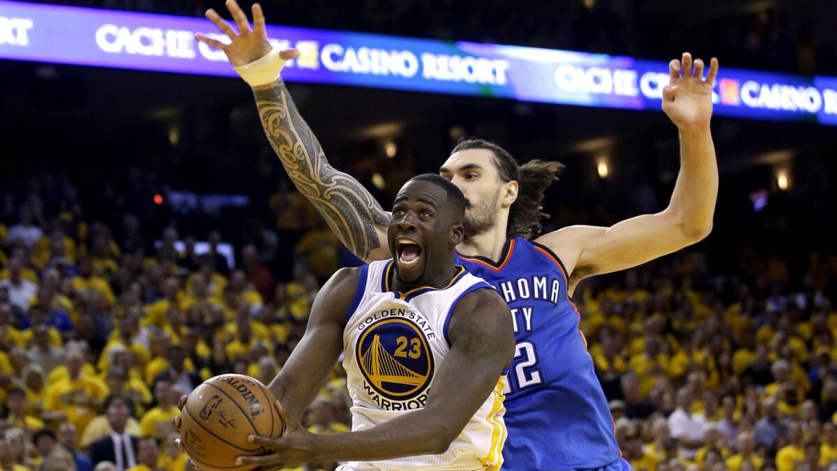 Warriors forward Draymond Green (23) drives past Thunder center Steven Adams for a layup in Game 1 on Monday.