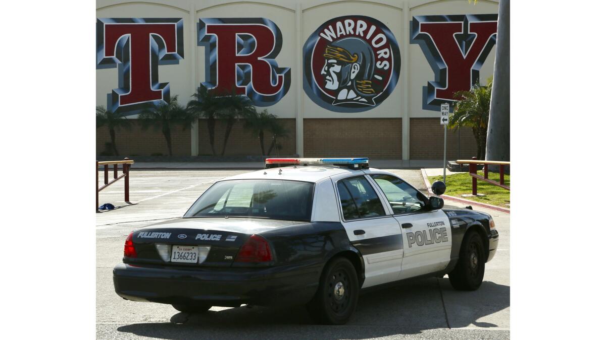 A police car is parked outside Troy High School in Fullerton, where two students were detained after allegedly threatening a school shooting.