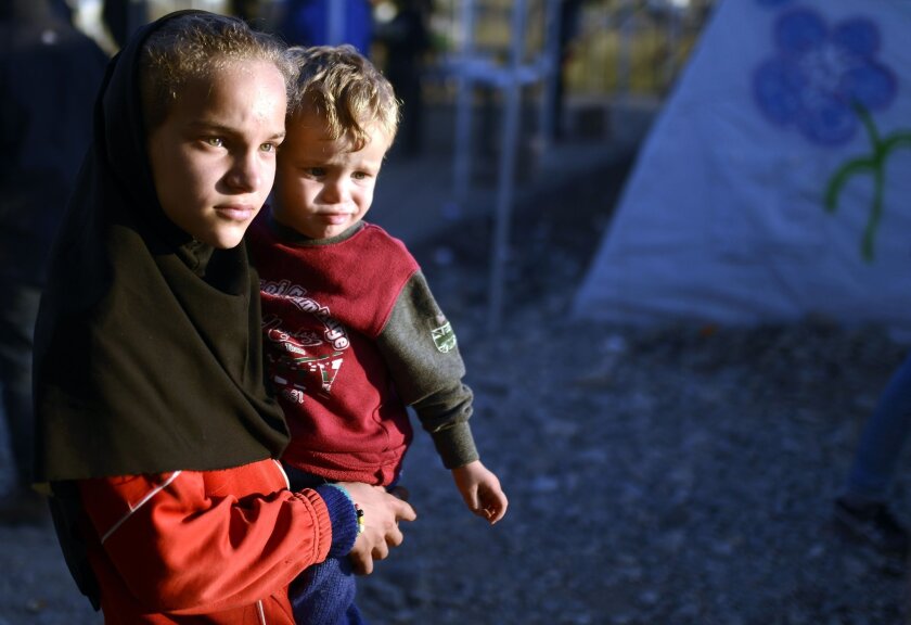 A girl carries a boy as migrants and refugees wait for a train heading to Serbia from the Greek-Macedonian border on November 5, 2015.