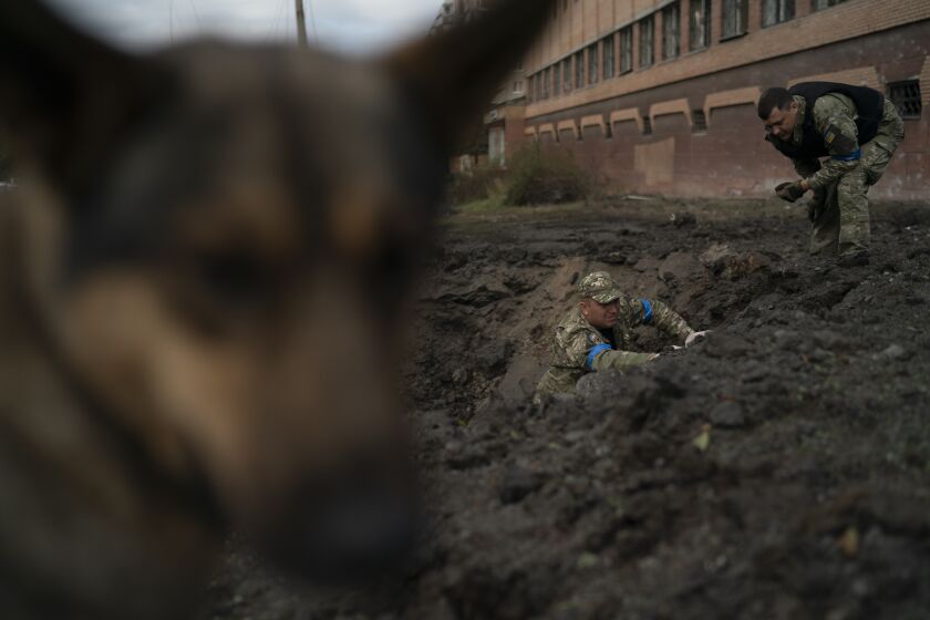 Policías ucranianos recolectan fragmentos de un cráter para determinar el tipo de munición de un ataque ruso, el jueves 29 de septiembre de 2022, en Kramatorsk, Ucrania. (AP Foto/Leo Correa)