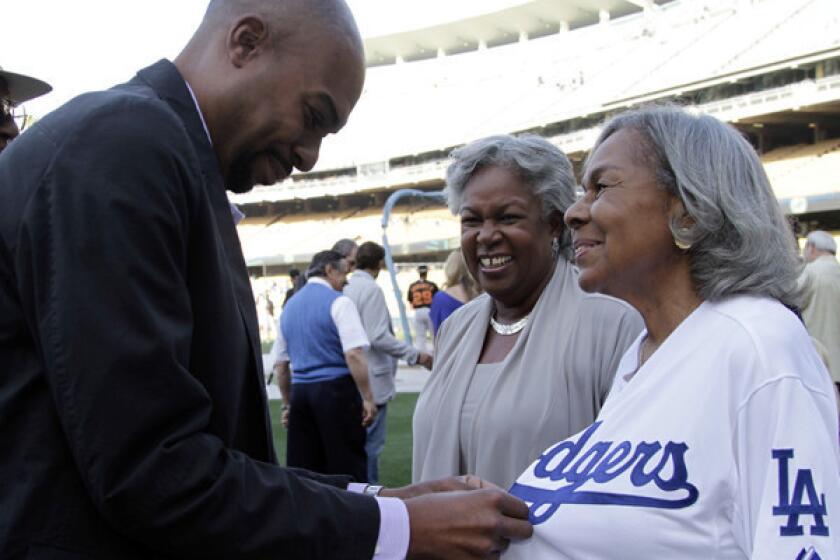Sharon Robinson looks on as her son, Jesse, helps Rachel Robinson, Jackie¿s widow, with a jersey at Dodger Stadium in May. Sharon will join the Dodgers' board of directors before next season.