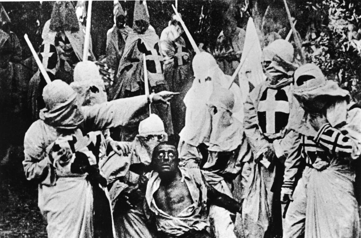 Actors costumed in the full regalia of the Ku Klux Klan chase down a white actor in blackface in a still from "The Birth of a Nation."