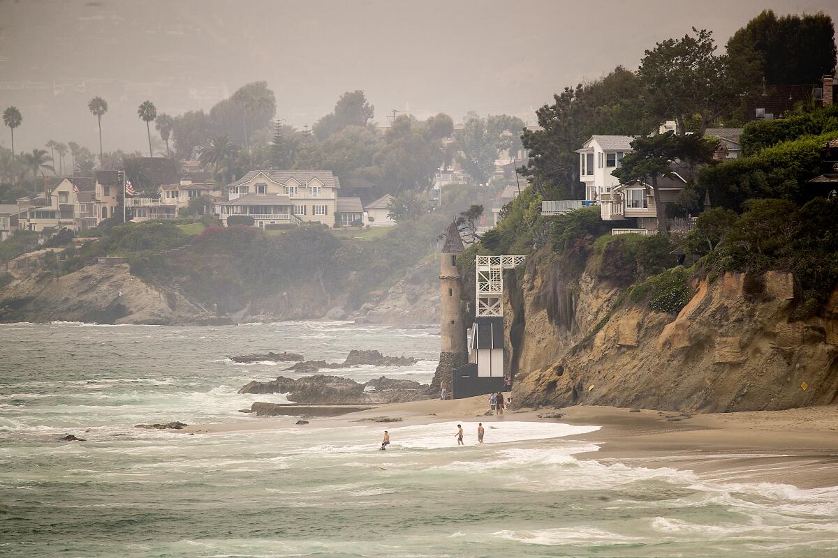Beachgoers frolic in the water in front of a tower at Victoria Beach, south of Moss Cove in Laguna Beach.