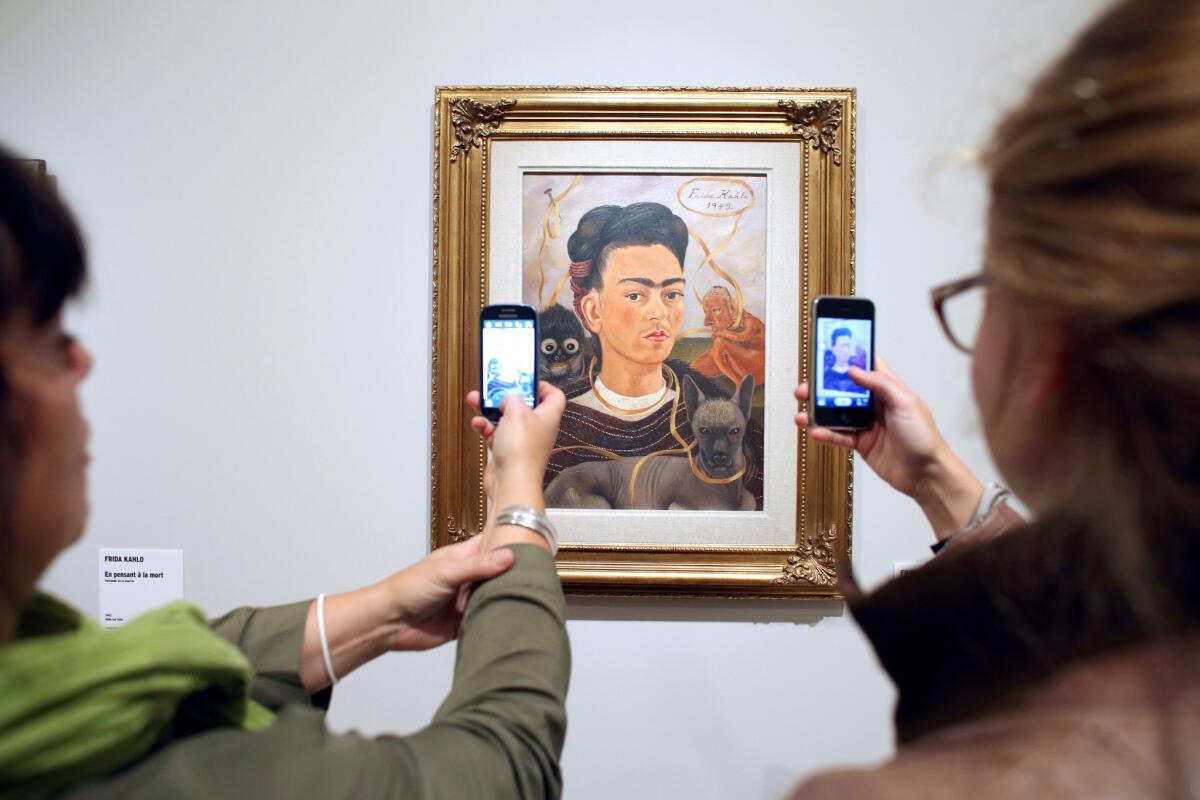 Women take pictures of an autoportrait by Mexican painter Frida Kahlo during the exhibition "Frida Kahlo / Diego Rivera Art in fusion" at the Musée de l'Orangerie in Paris.