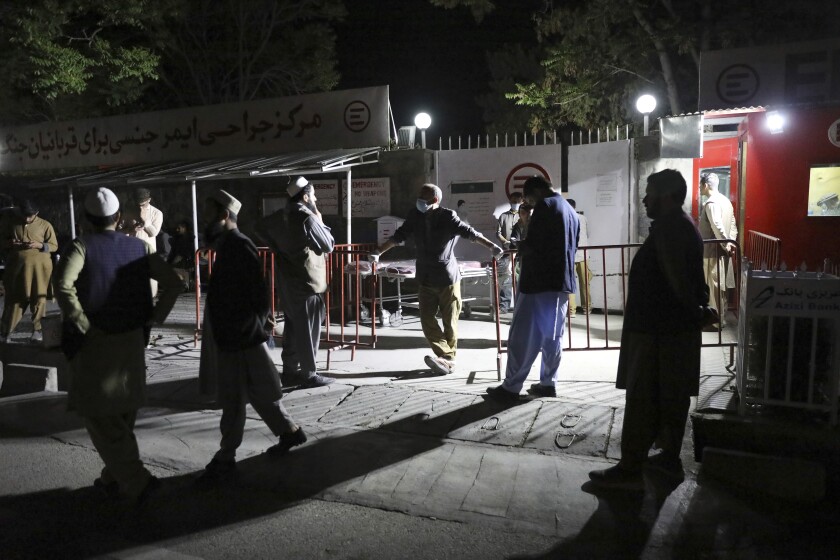 Afghans wait outside the hospital to see their relatives in Kabul, Afghanistan
