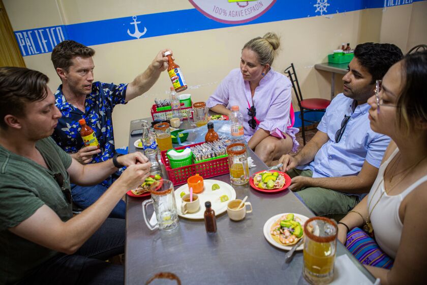 MEXICO CITY - JULY 06: Tyler Hansbrough, second from left, has led an Airbnb experience called Tyler's Taco Tours since before the pandemic. He describes types of hot sauces to his tour group at a restaurant on Wednesday, July 6, 2022 in Mexico City. (Celia Talbot Tobin for the Times)