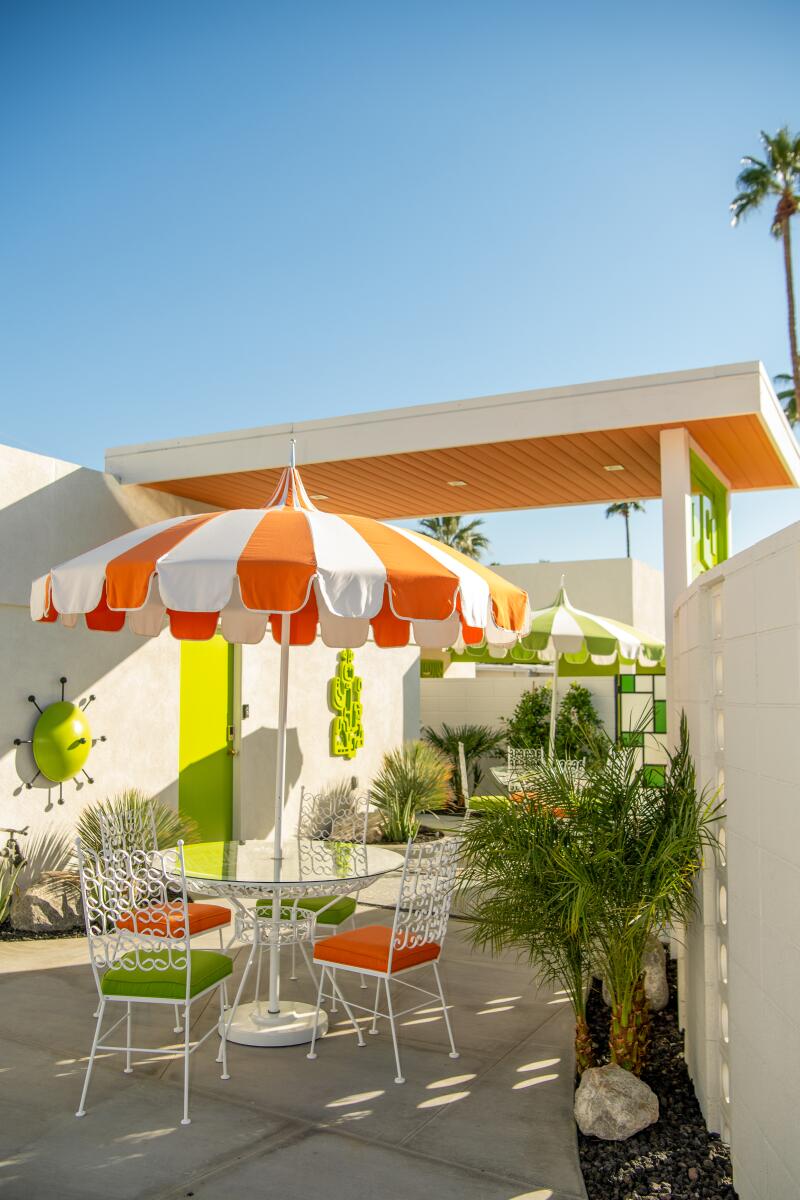 Patio furniture under a white and orange striped umbrella at the Shag house in Palm Springs