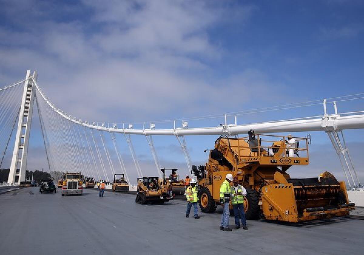 Workers pave the deck of the eastern span of the newly constructed San Francisco-Oakland Bay Bridge.