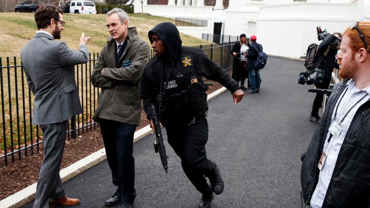 A Secret Service officer rushes past reporters after a vehicle rammed into a security barrier near the White House on Friday.