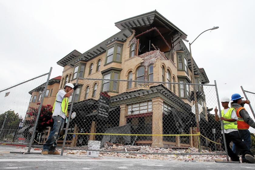 Workmen put up chain-link fencing around a badly damaged building in downtown Napa last year.