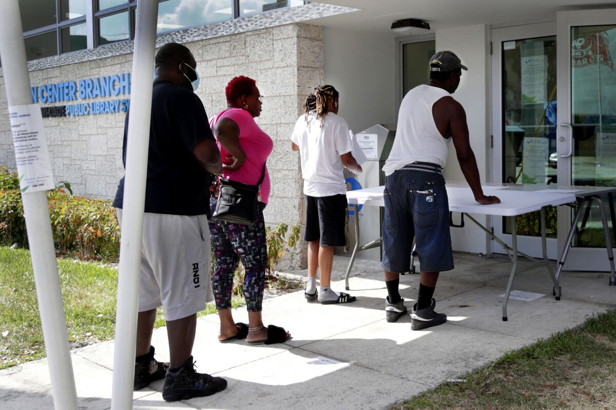 Restaurant worker Glen Pile, left, waits in line to get an unemployment form at a Miami-Dade County library.