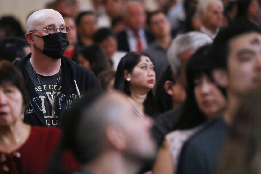 LOS ANGELES, CALIFORNIA - FEBRUARY 26: : A worshipper (L) wears a face mask to protect against the coronavirus while sitting in a pew at the Cathedral of Our Lady of the Angels on Ash Wednesday on February 26, 2020 in Los Angeles, California. The worshipper said he was not sick but was wearing the mask out of an abundance of caution. Ash Wednesday marks the beginning of Lent and involves the placing ashes on the foreheads of Christian believers as a sign of repentance which occurs 40 days, excluding Sundays, before Easter. (Photo by Mario Tama/Getty Images)